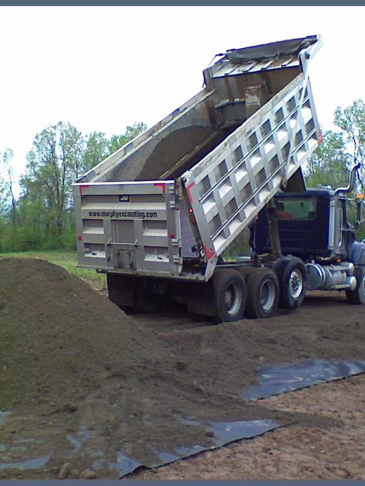 Dump truck unloading dirt for site preparation