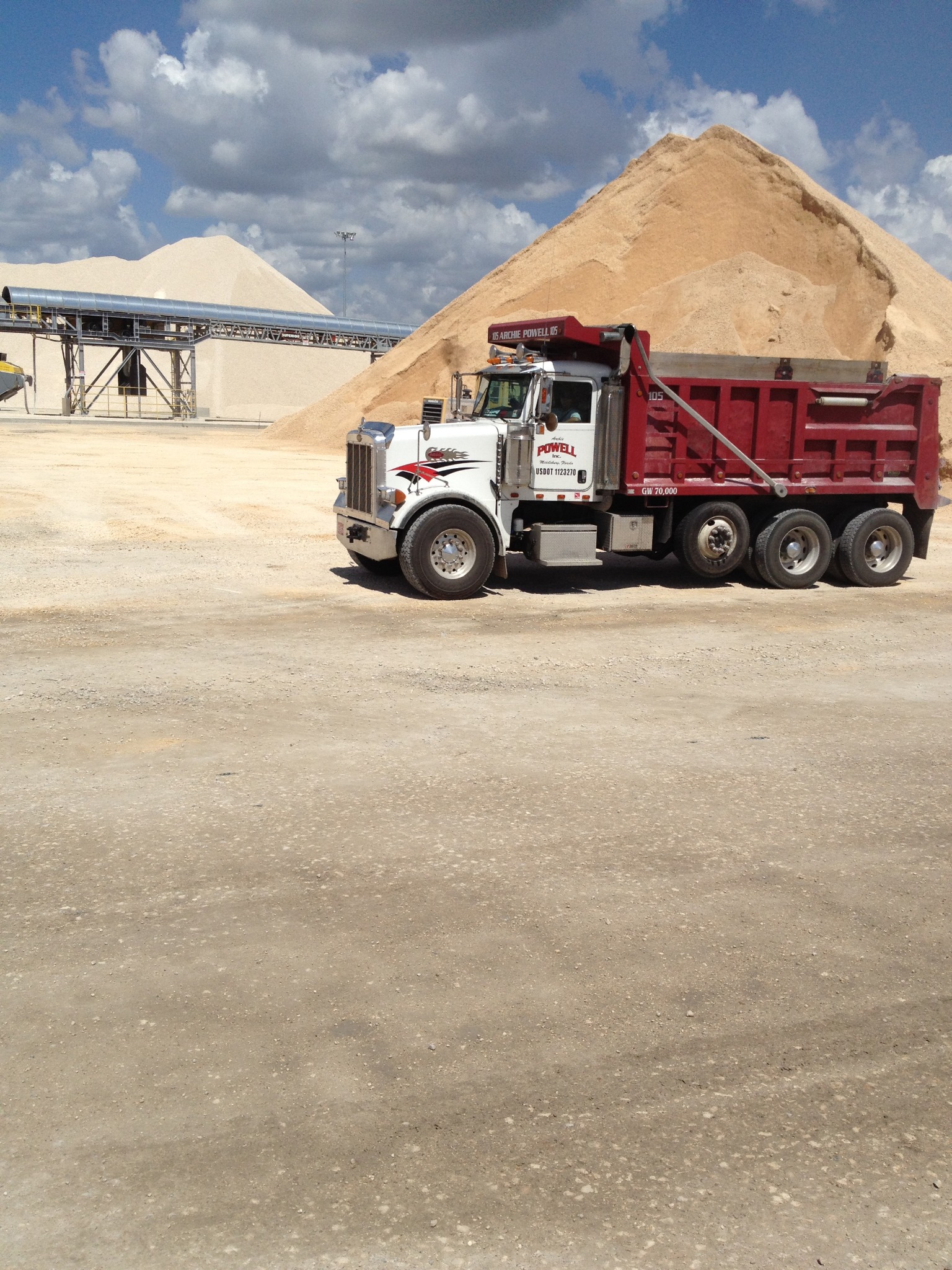 Archie Powell Inc. dump truck near large material piles